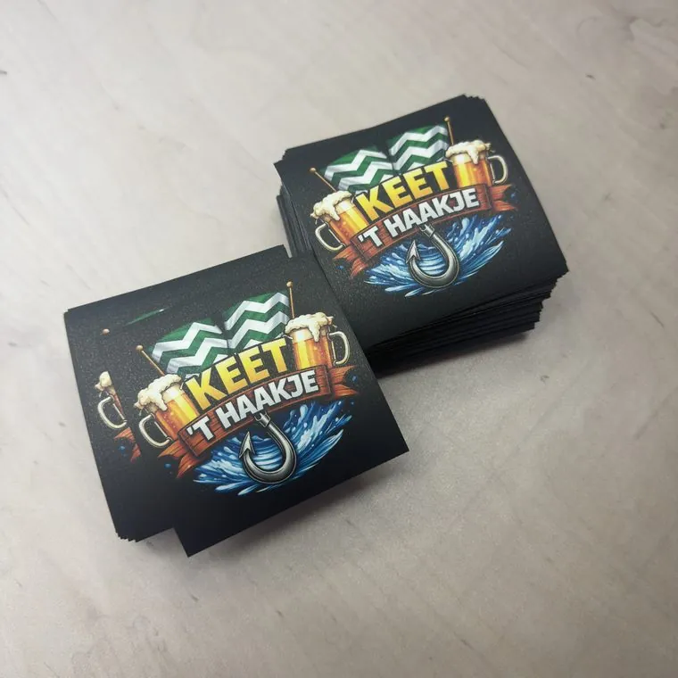 Stapel losse vierkante stickers met het logo Keet 't Haakje in kleur op een zwarte ondergrond